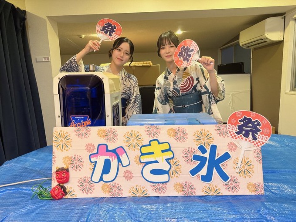浴衣姿のスタッフがうちわを持ってかき氷の屋台に立つ様子